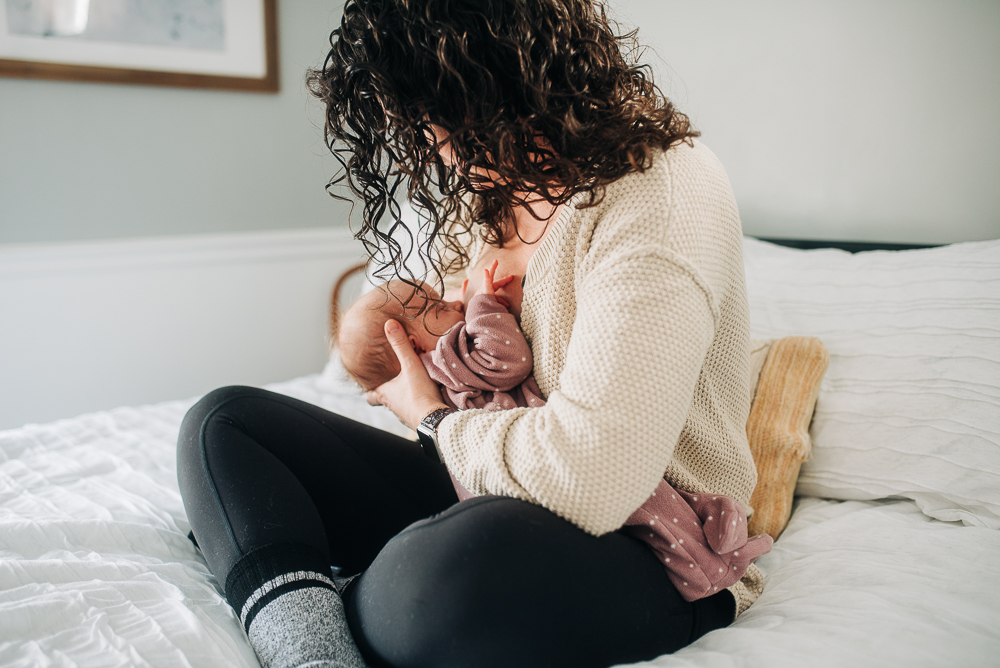 Mother nursing her baby in white bed. - Does breast milk change throughout the day?